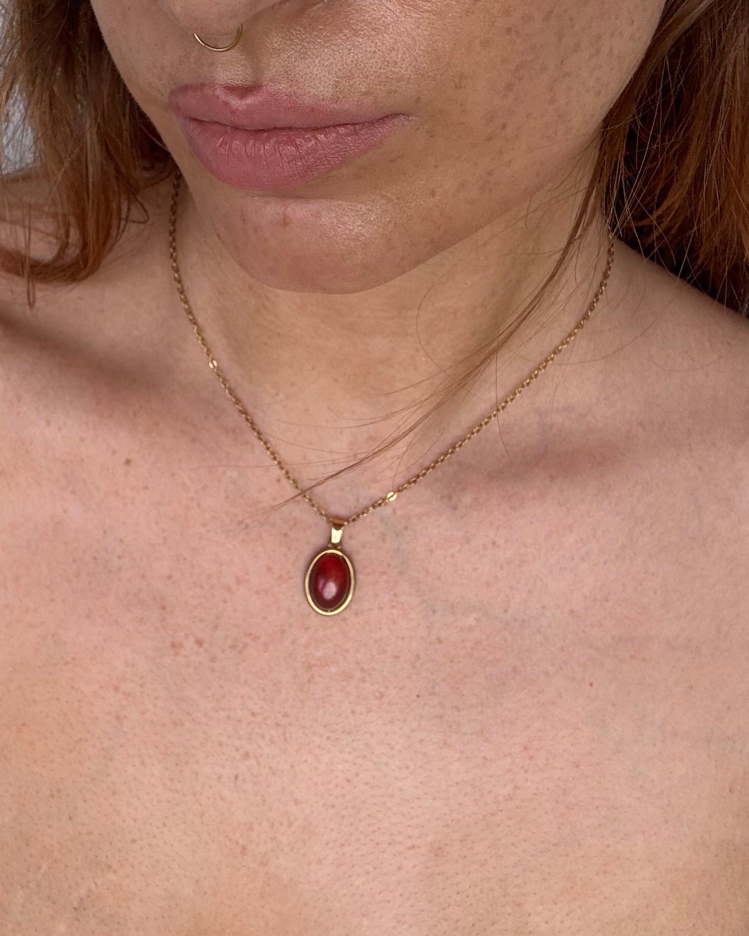 Person with red hair and blue eyes looking directly at the camera on a white floor.