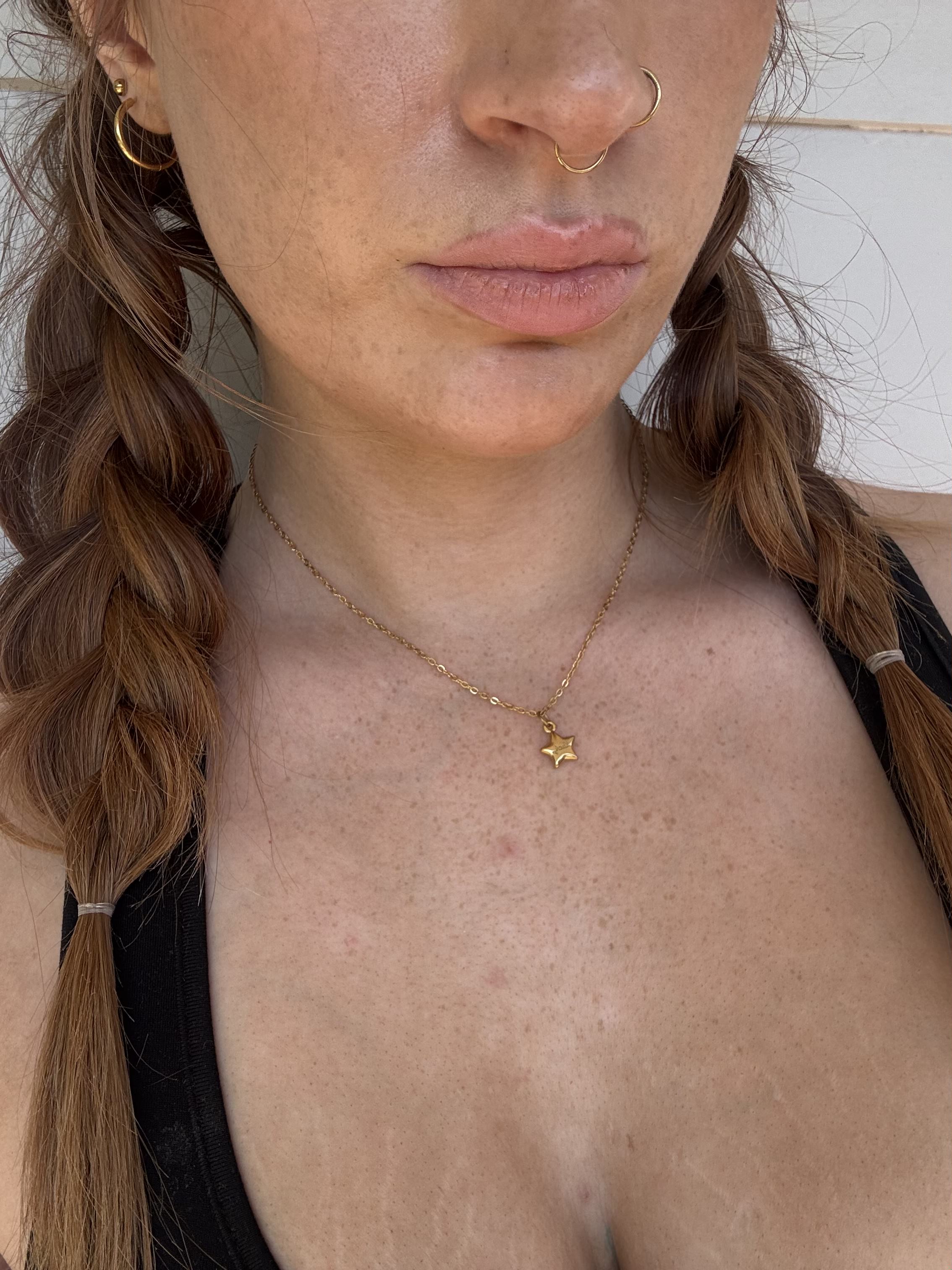 Close-up of a person wearing a gold necklace with star pendants.