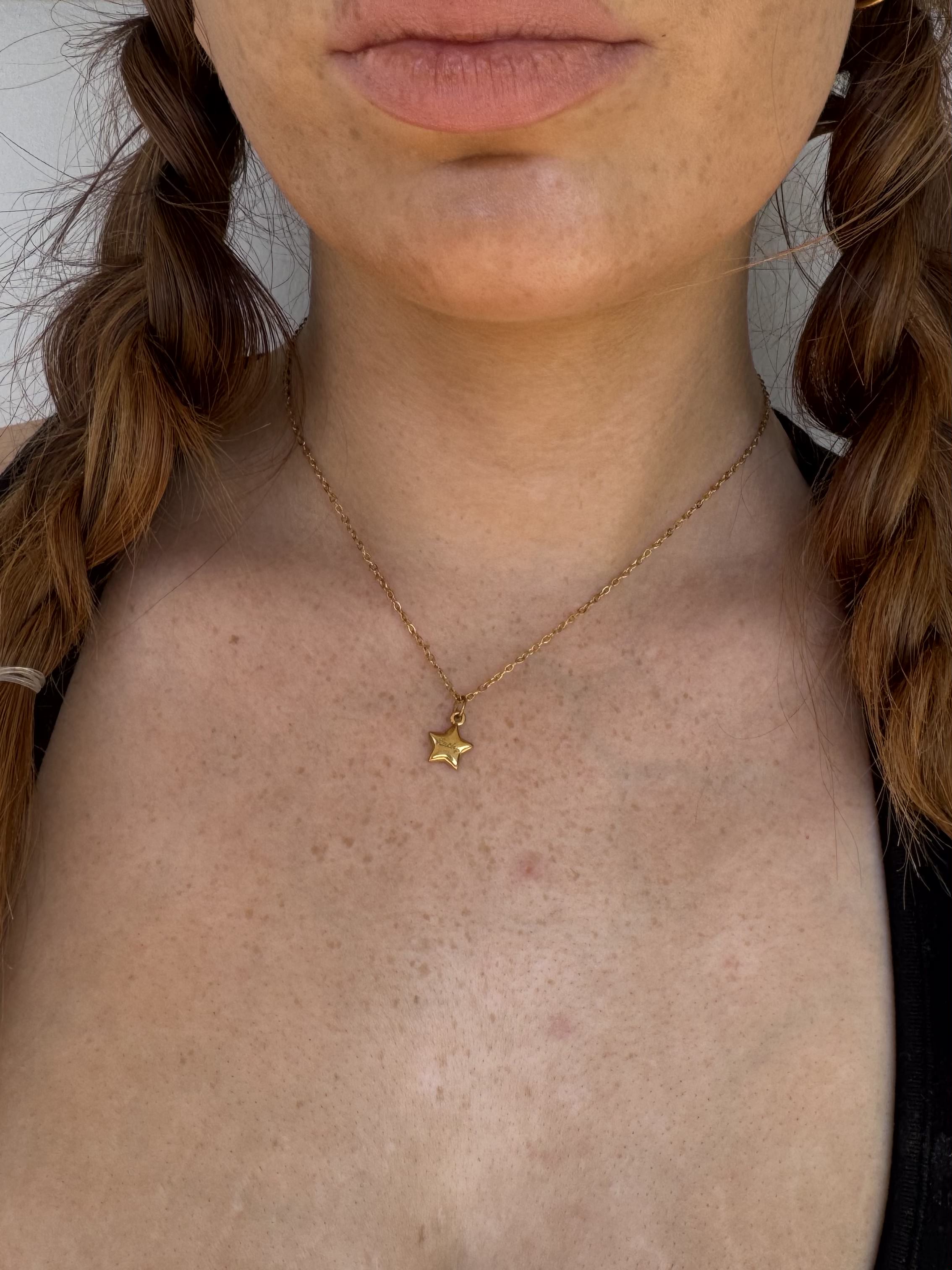 Person wearing a gold necklace with a star pendant