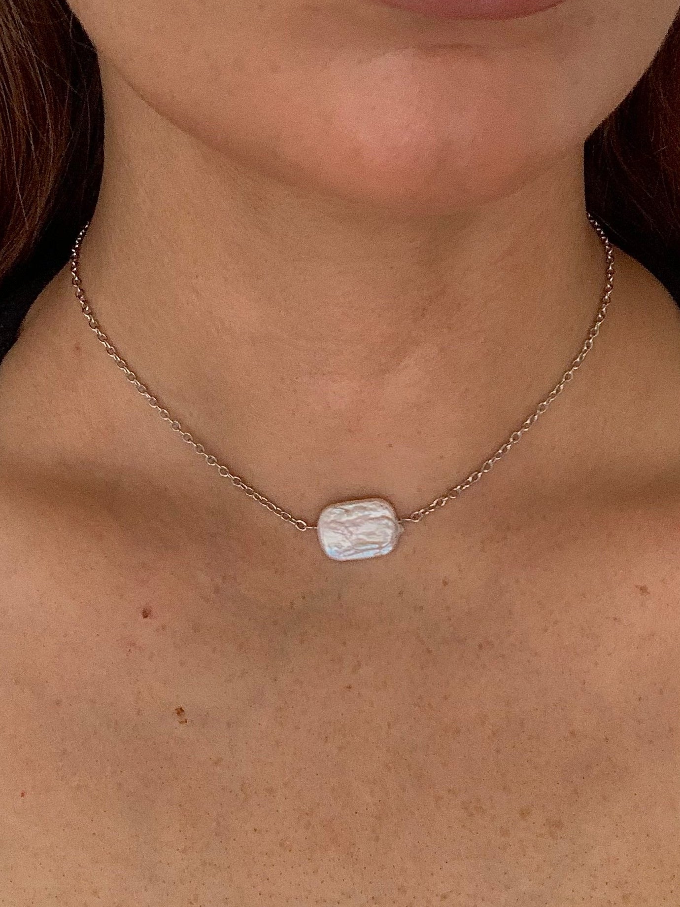Necklace with a rectangular pendant worn by a person