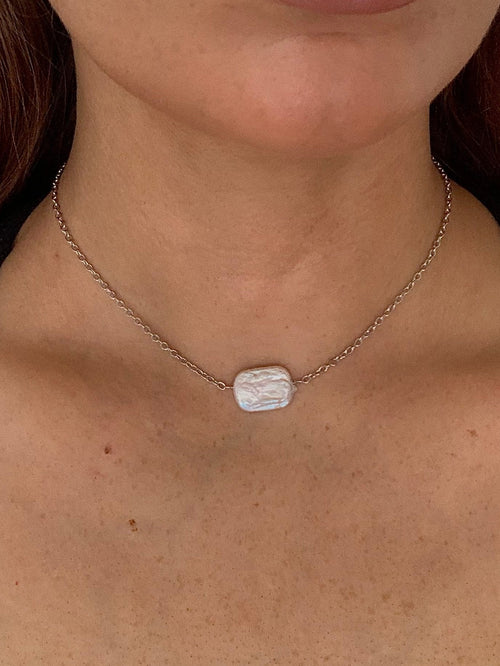 Necklace with a rectangular pendant worn by a person