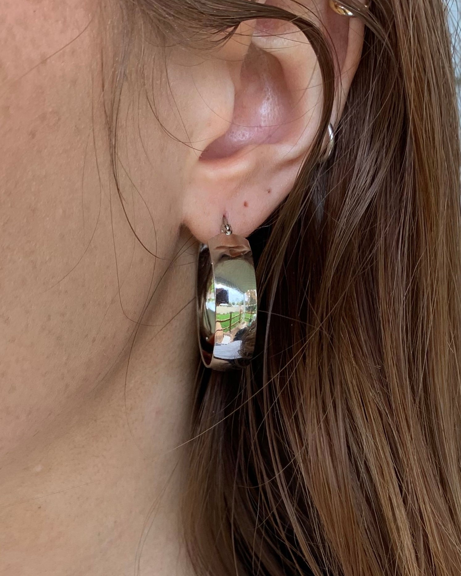 Close-up of a person's ear with an earring, hair partially covering the face.