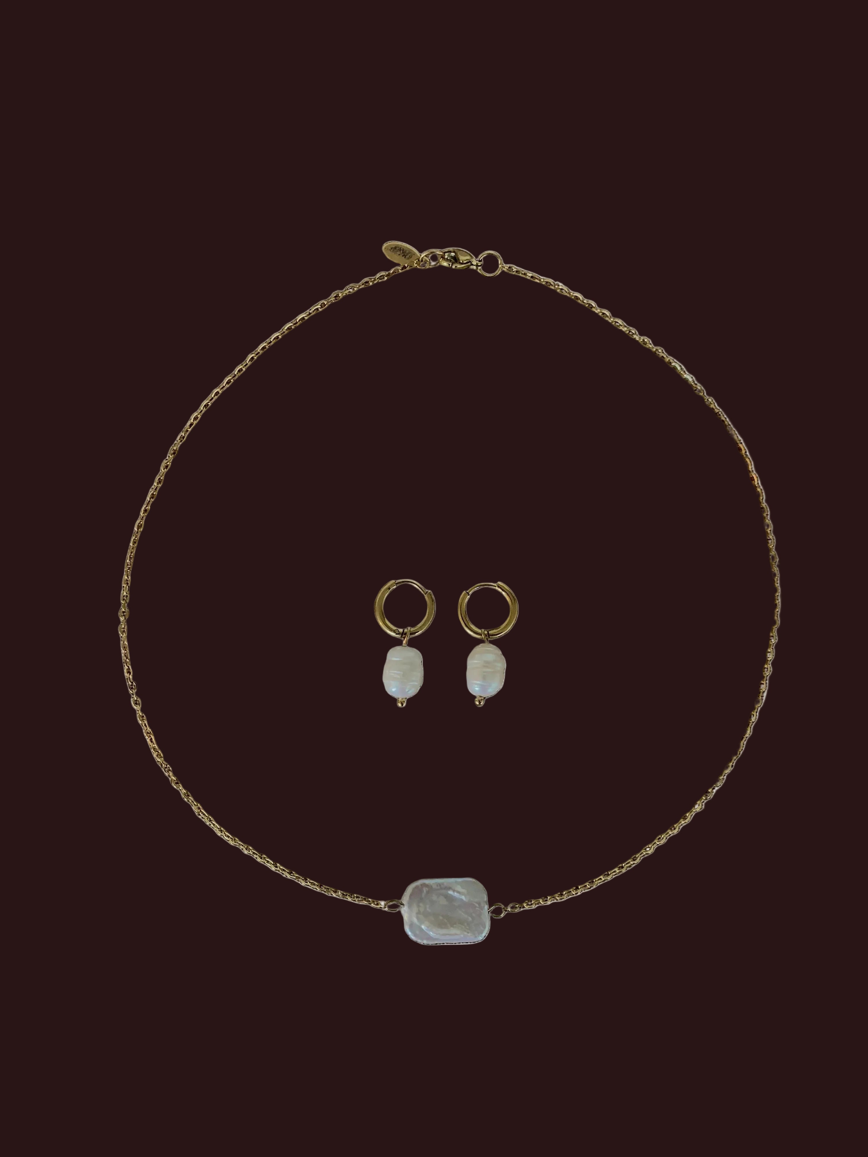 Jewelry set including a necklace, earrings, and a pendant on a brown fabric background