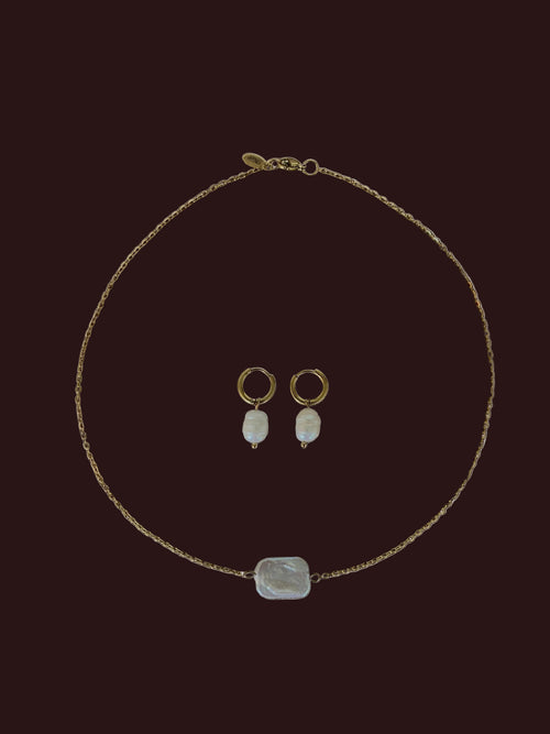 Jewelry set including a necklace, earrings, and a pendant on a brown fabric background
