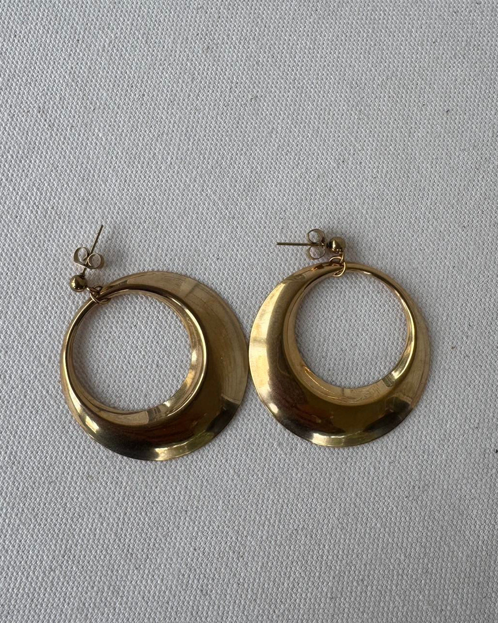 Pair of gold hoop earrings on a light gray background