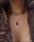 Necklace with a red pendant worn by a person with fur clothing.