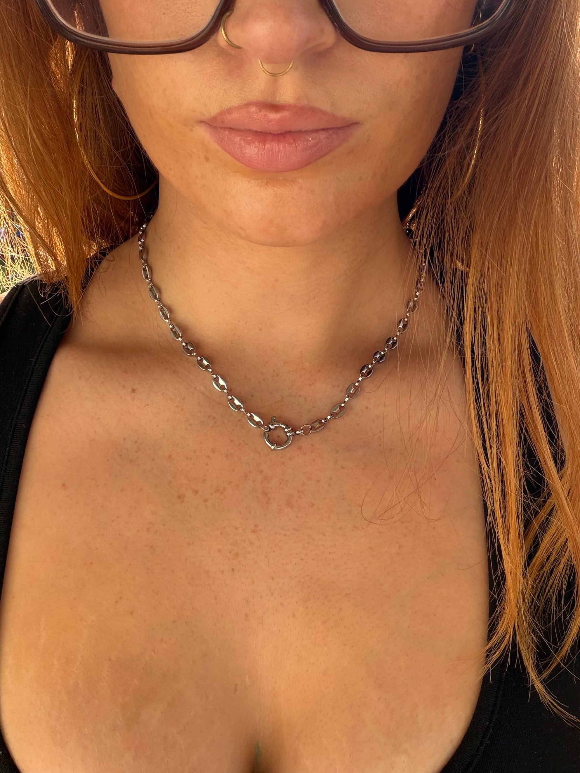 Close-up of a person wearing a chain necklace with a blurred background