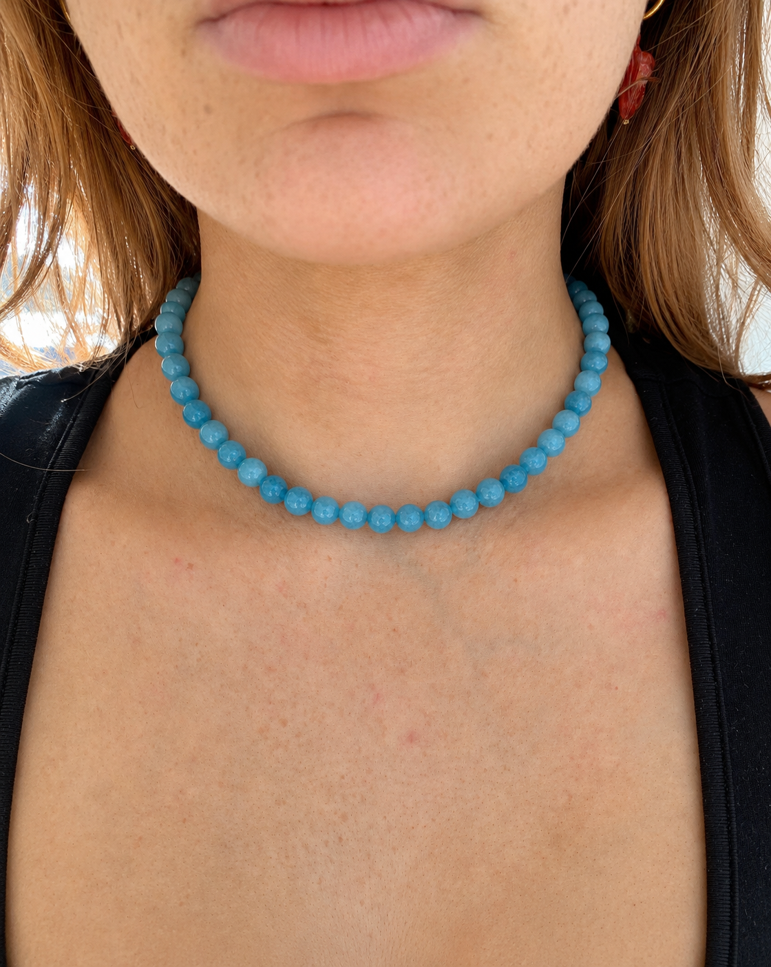Close-up of a person wearing a turquoise beaded necklace.