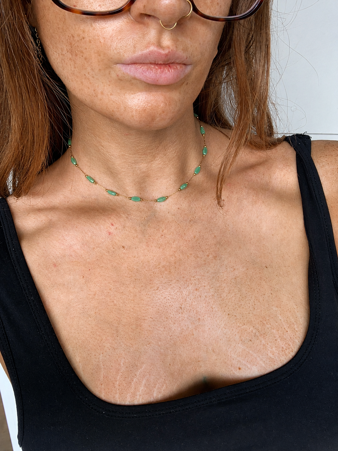 Close-up of a person's neck with a green line drawn around it, against a neutral background.