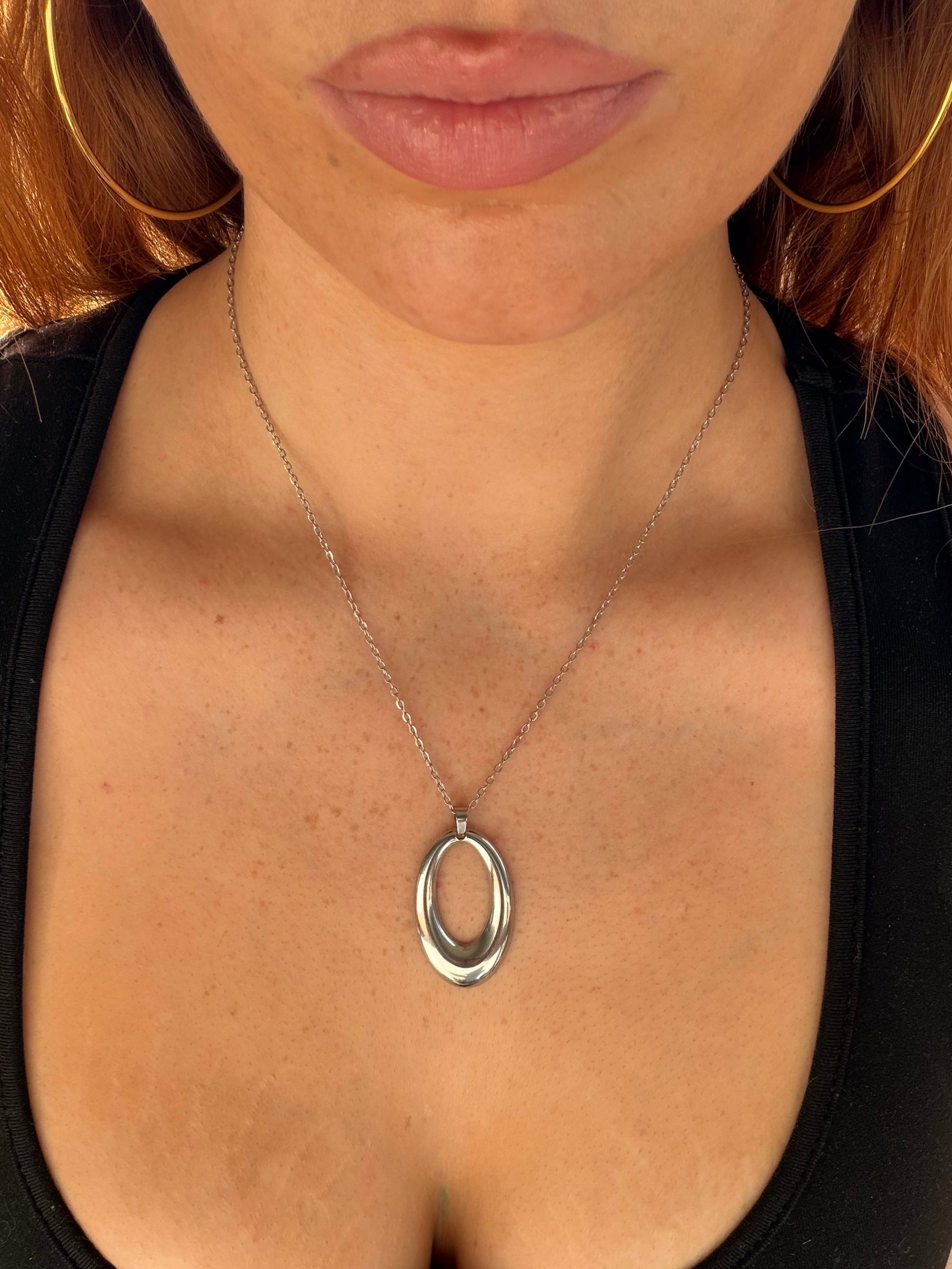 Close-up of a necklace with a pendant on a person wearing a black top.