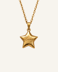 A gold star-shaped pendant necklace engraved with the word 'Lucky' in cursive, suspended from a gold link chain against a light cream background.