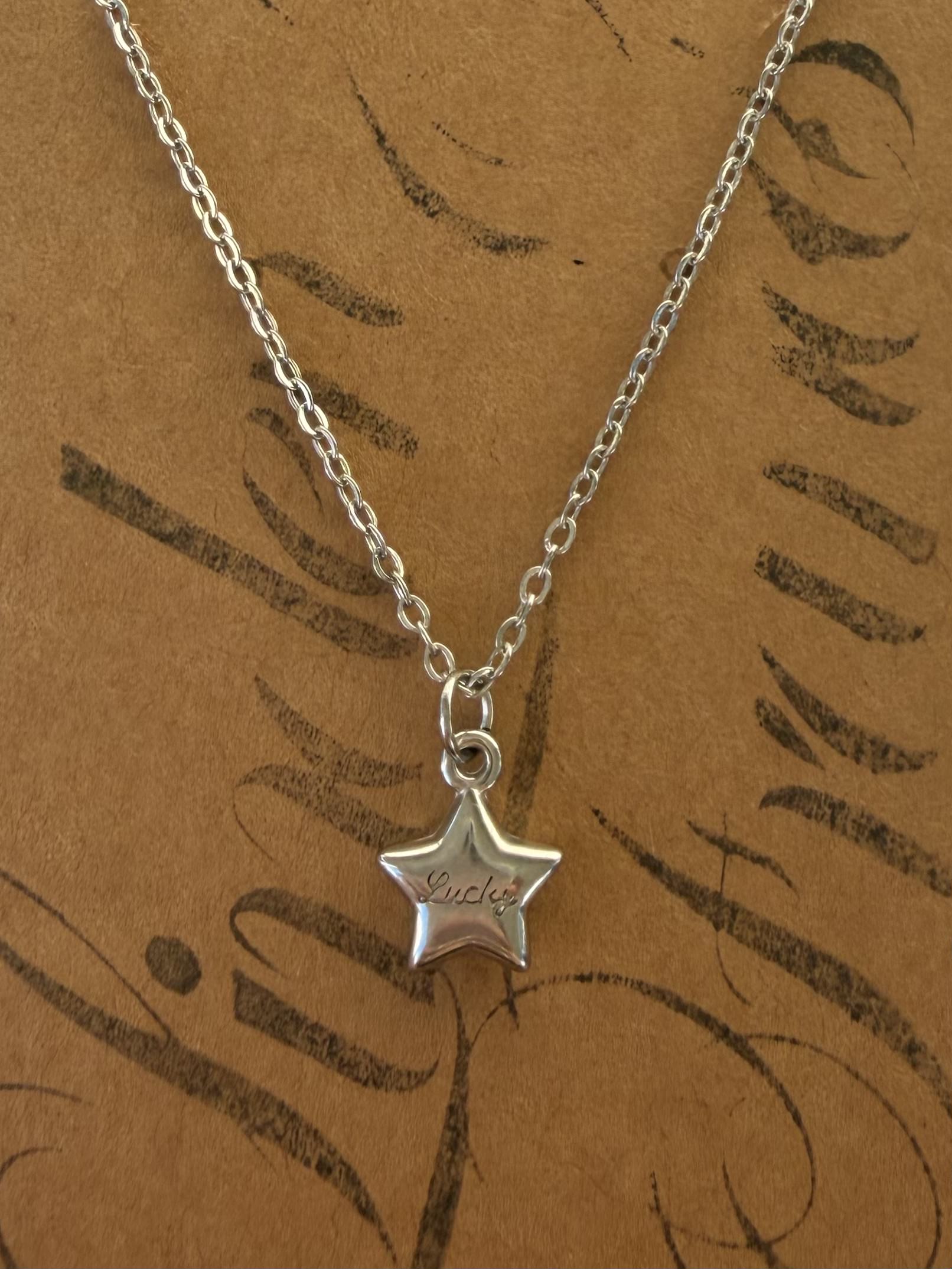 Silver star pendant necklace on a brown card with leaf patterns