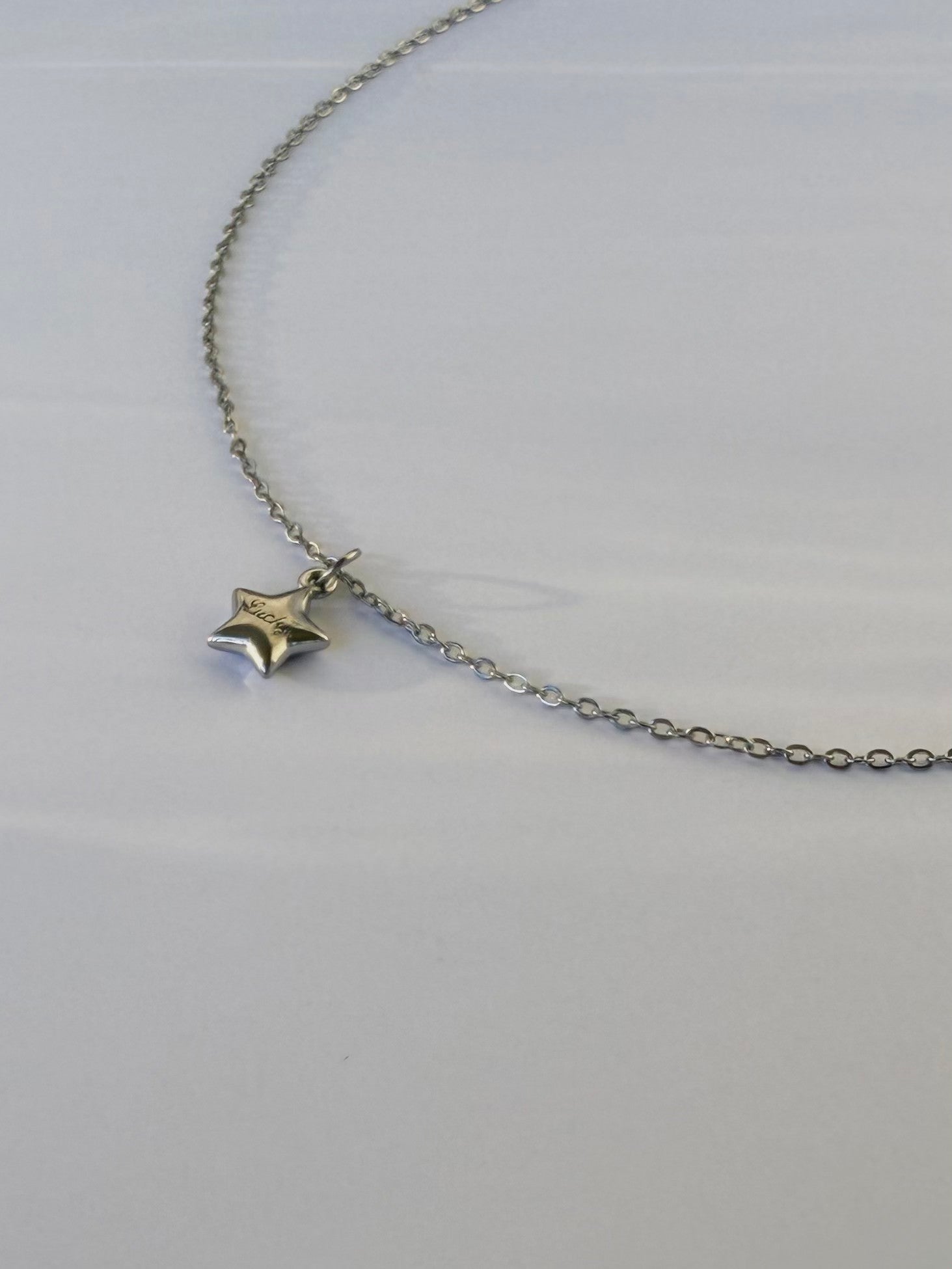 Silver star pendant necklace on a light gray background