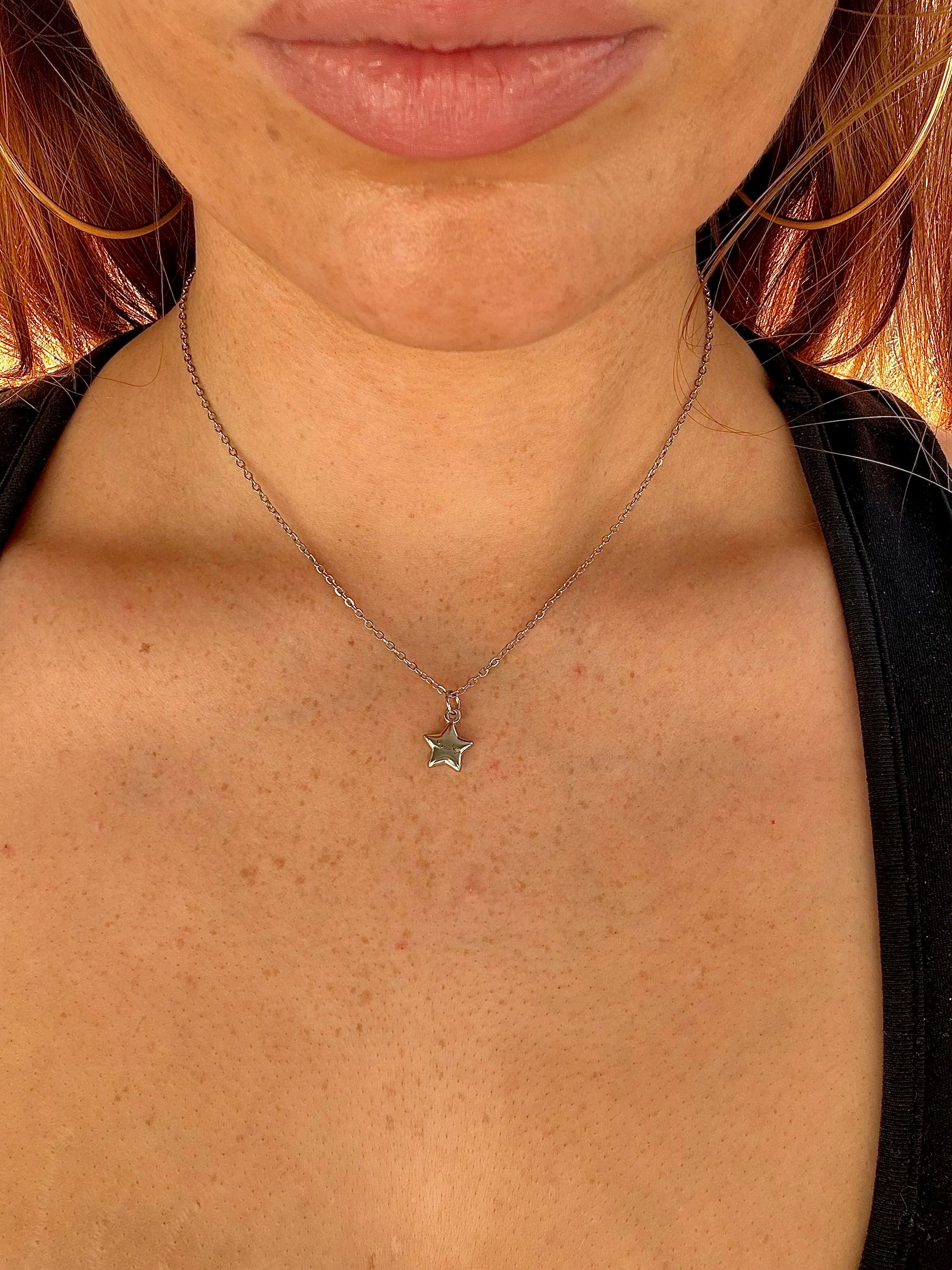 Star-shaped pendant necklace on a person's neck with a blurred background