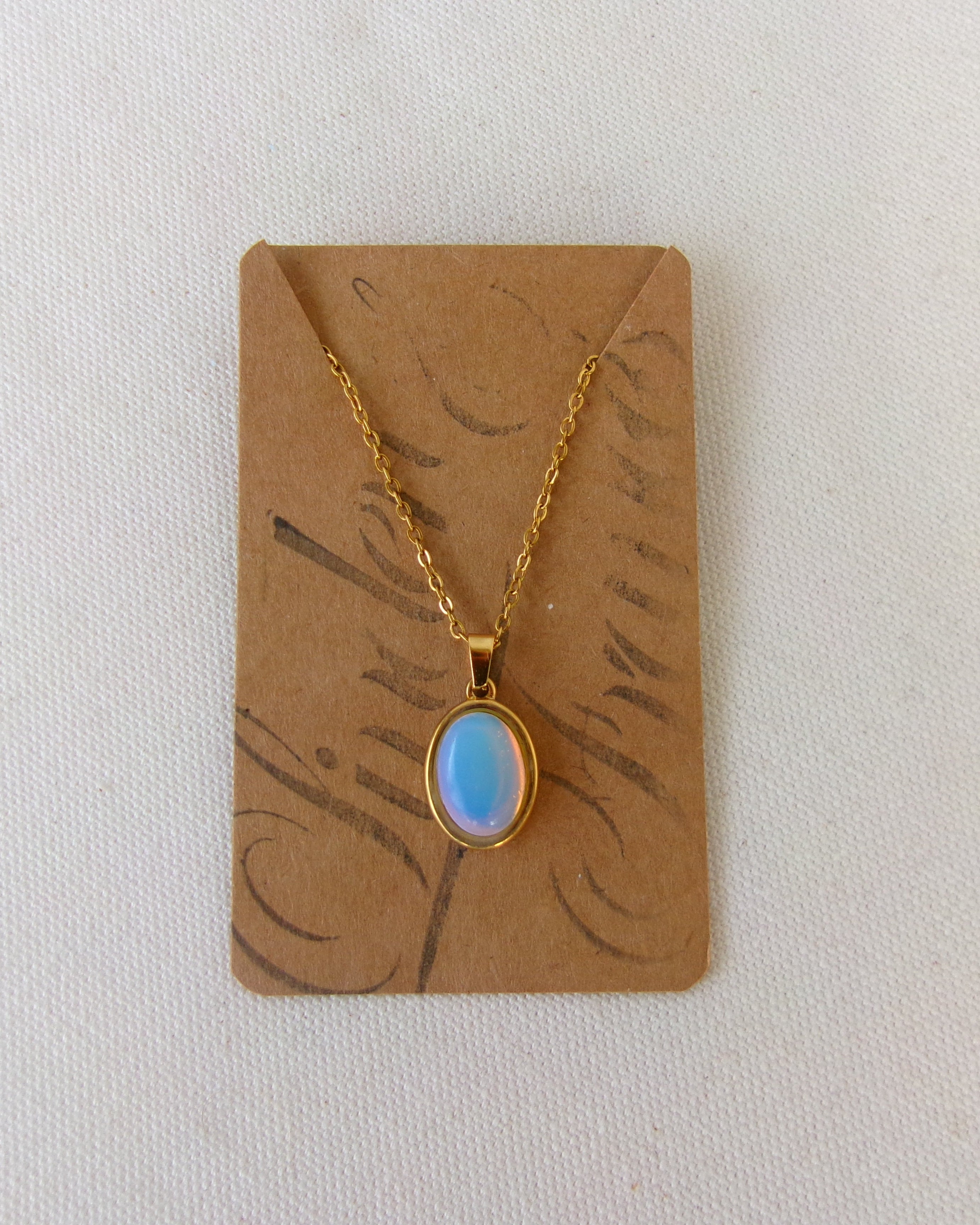 Necklace with a blue pendant on a brown card against a white background