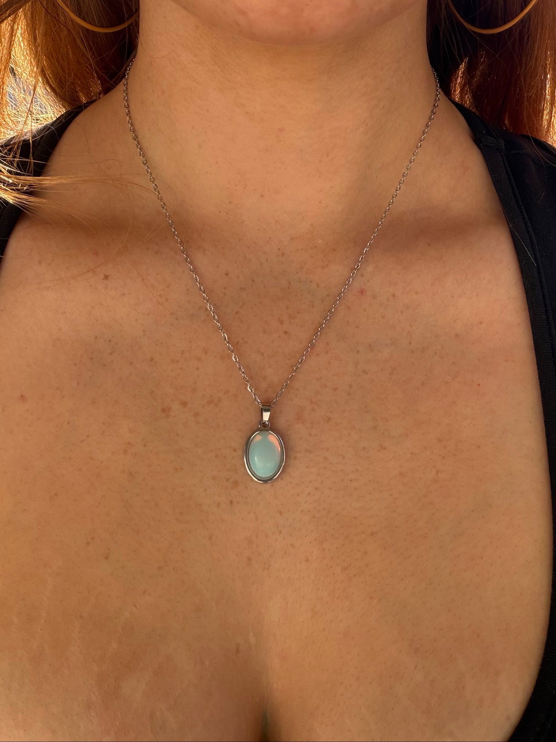 Close-up of a necklace with a pendant on a person wearing a black top.