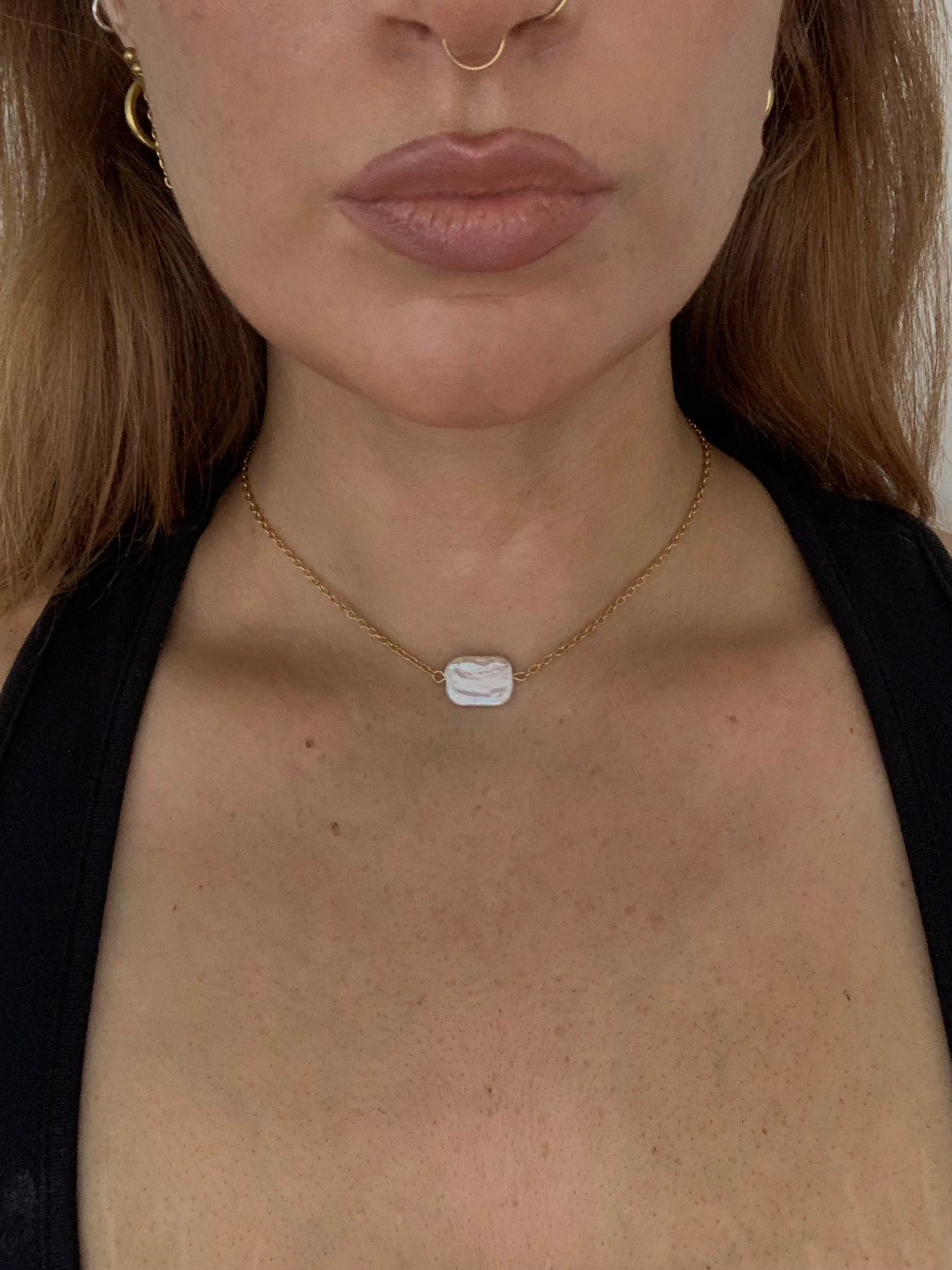 Necklace with a pearl pendant worn by a person