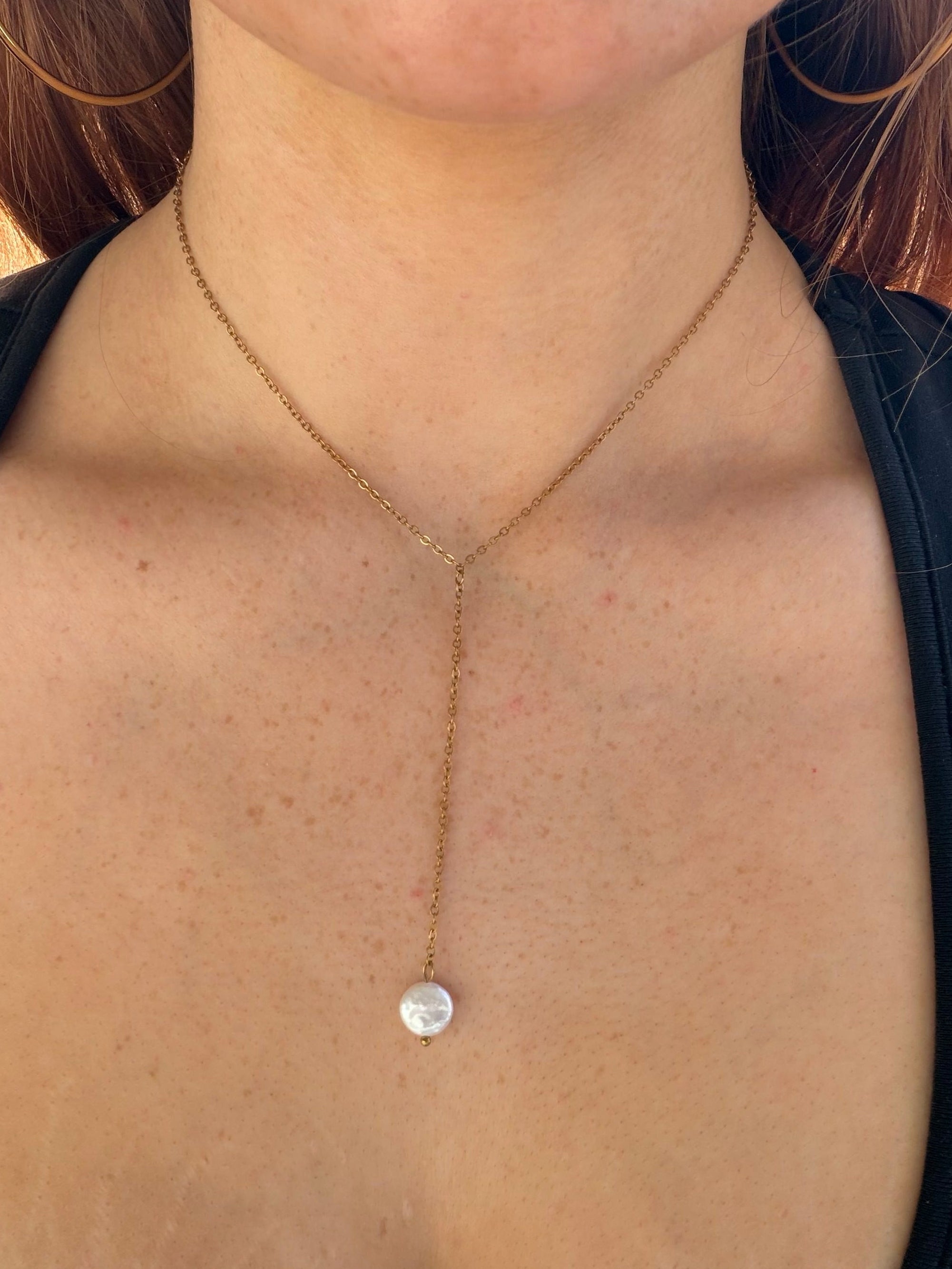 Close-up of a necklace with a  pearl drop necklace on.