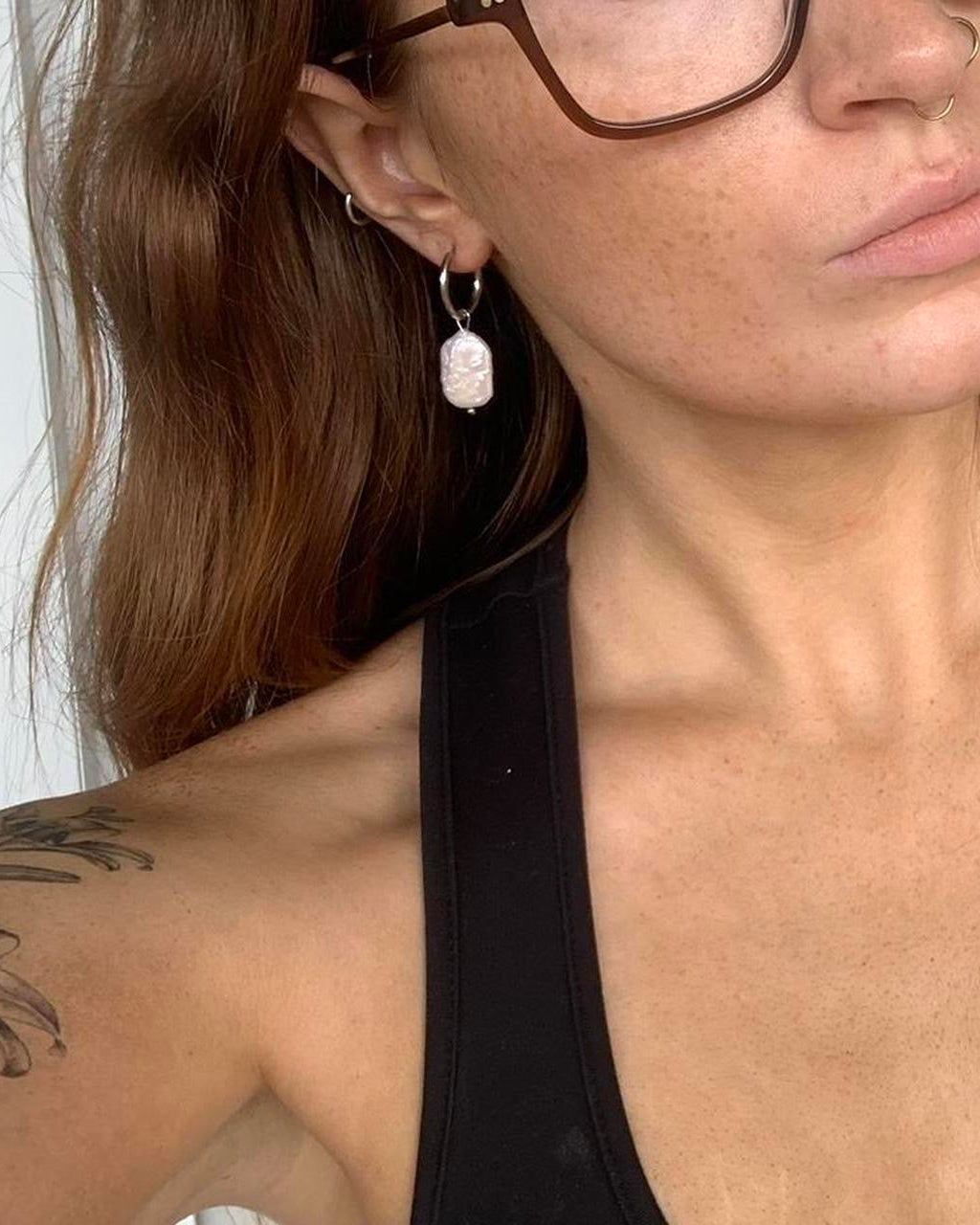 woman with glasses wearing pearl hoop earrings