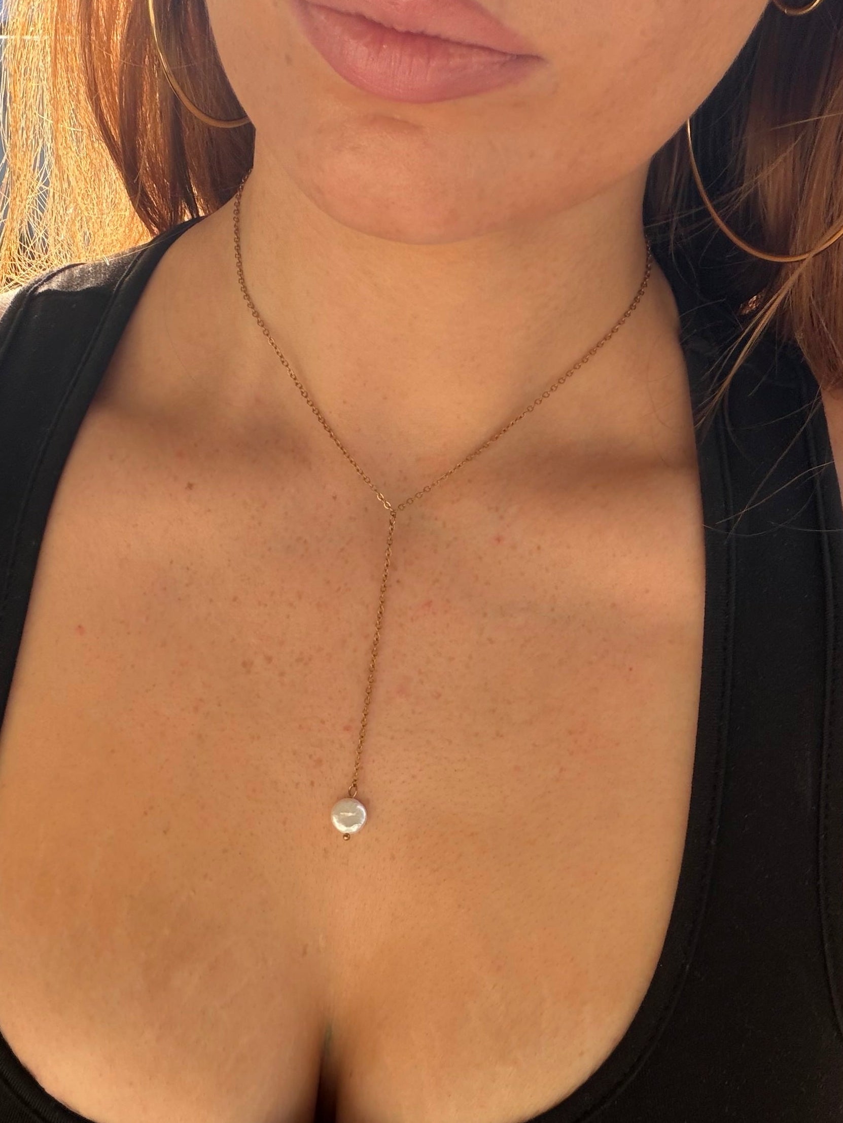 person wearing a choker style necklace with a pearl drop aspect.