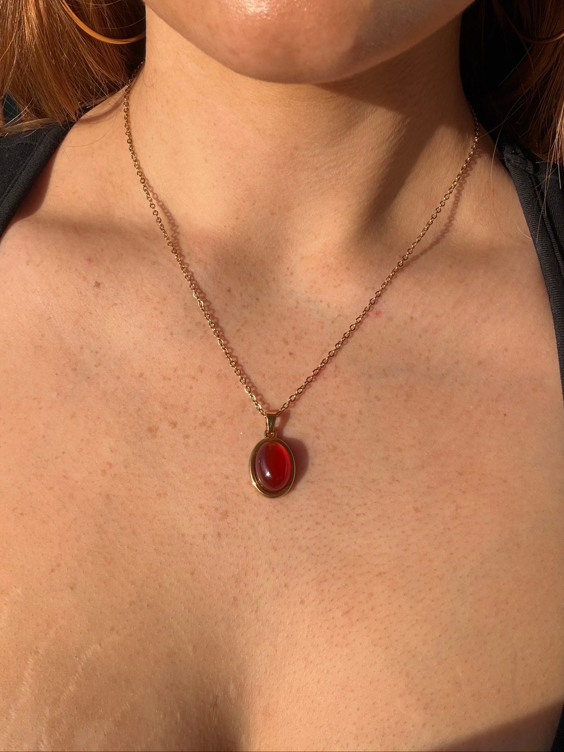Close-up of a person wearing a necklace with a red pendant.