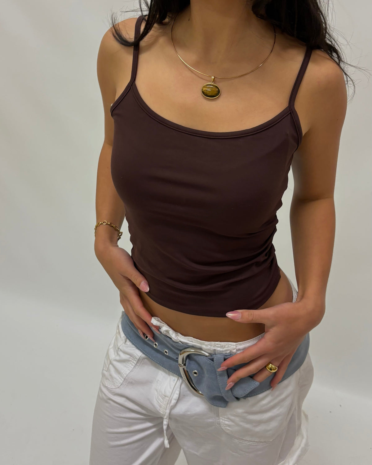 A woman wearing a thin wire necklace with a large horizontal tigers eye pendant.
